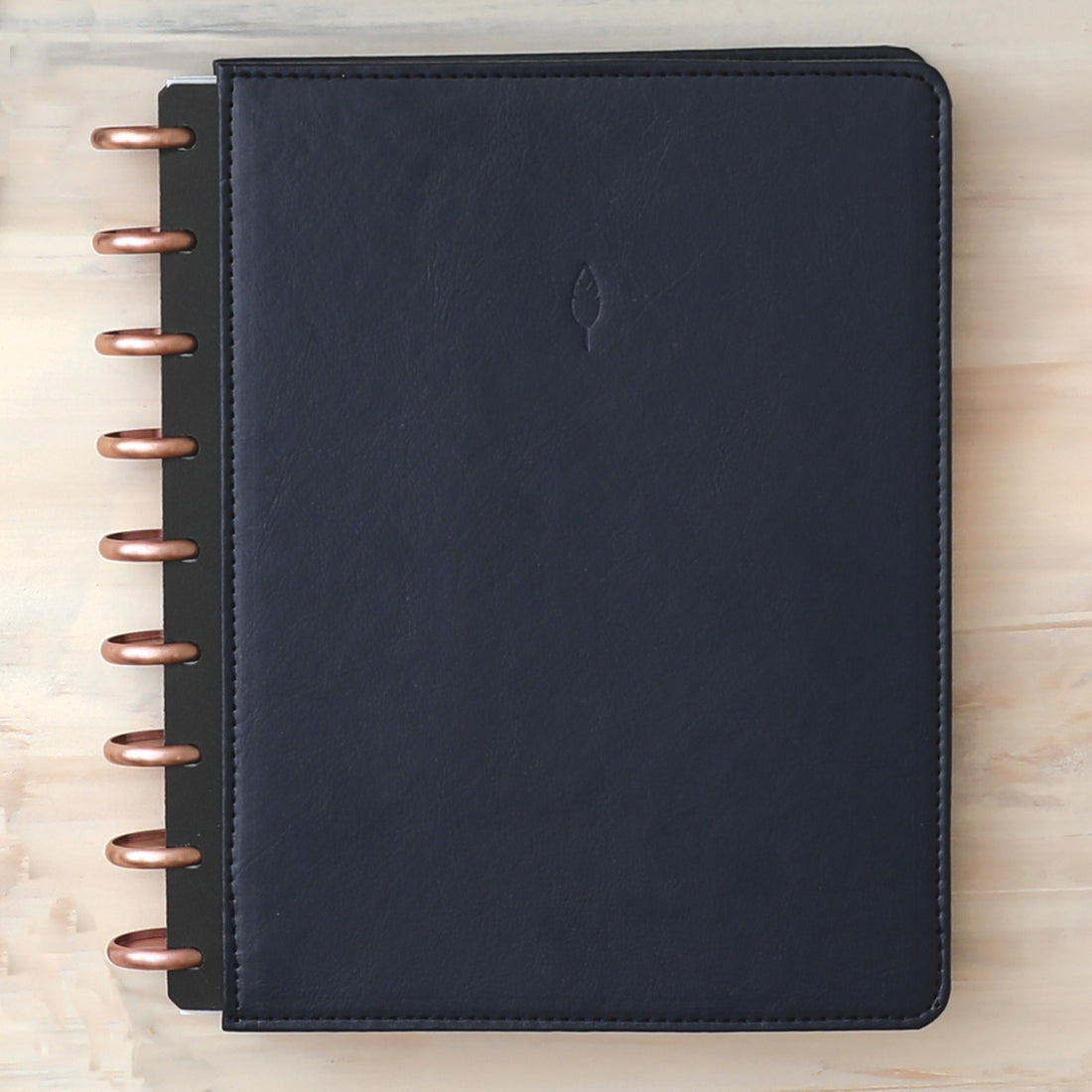 Vegan leather deep navy blue cover with embossed quill logo, gold discs, and in a 7x9 planner size